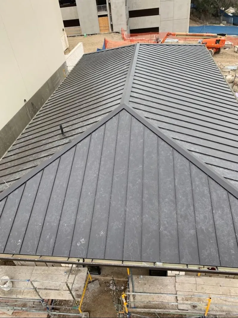 Commercial metal roof construction with crane equipment in Martinez